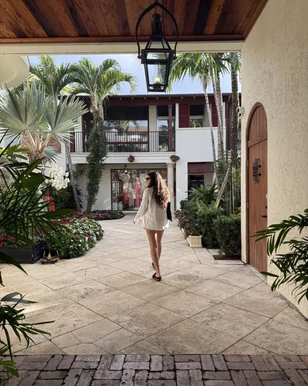 Mediterranean Revival courtyard with an arched wooden door, lantern and palms in Palm Beach County